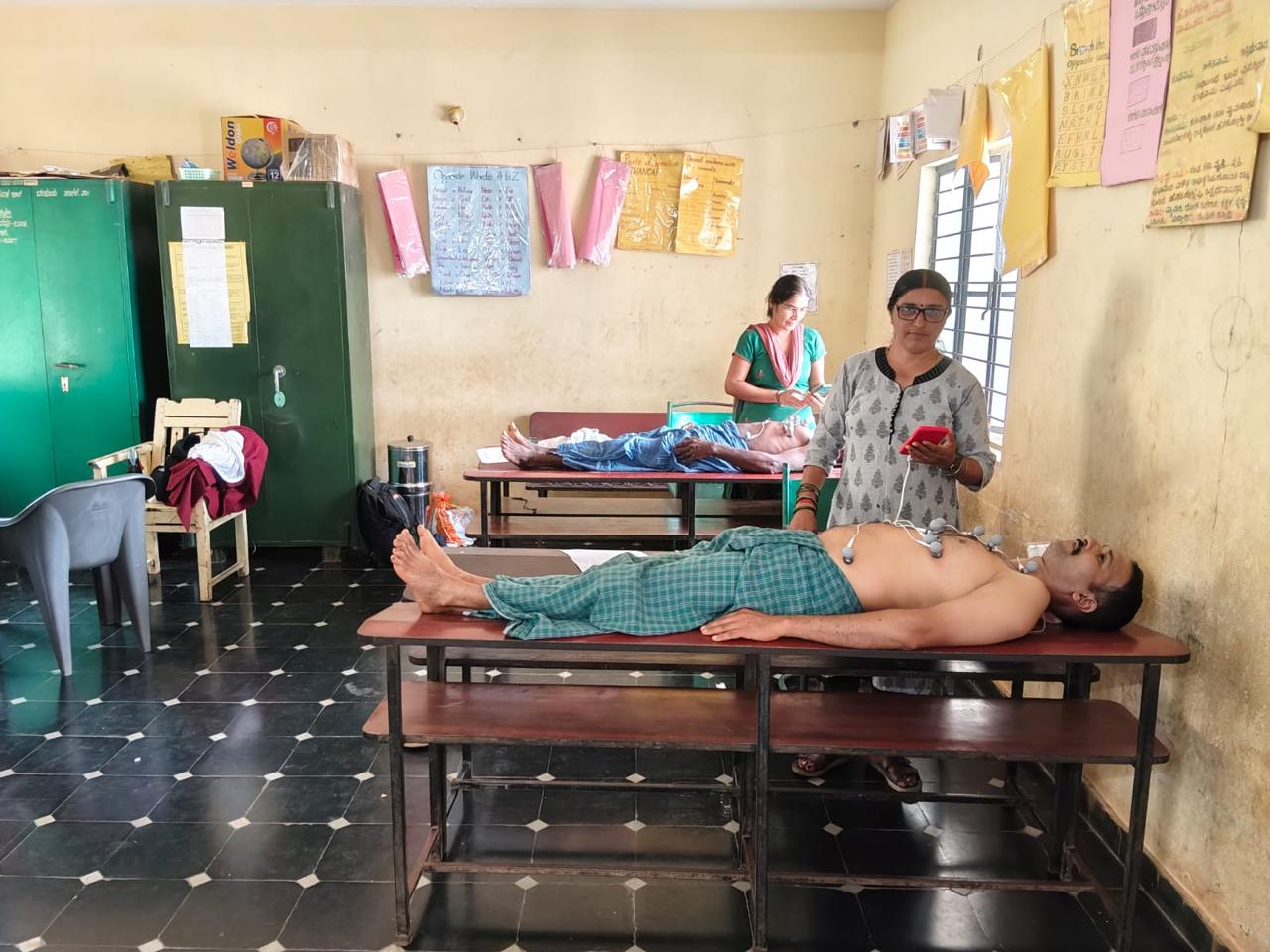 Volunteers conducting portable ECG screening in a village classroom